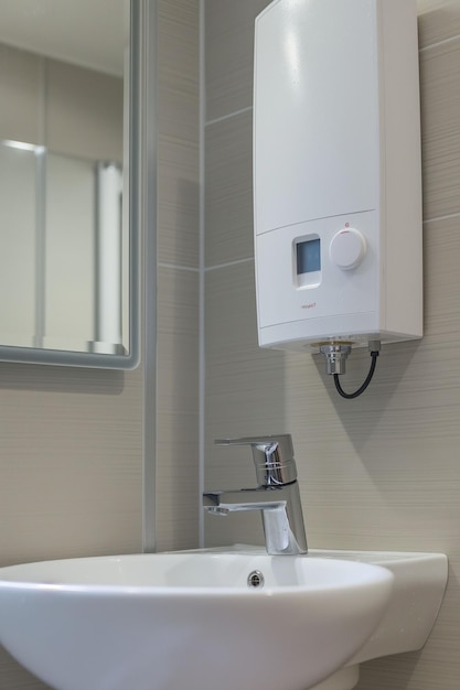 Closeup water heater in a modern bathroom with mirror and washbasin sink