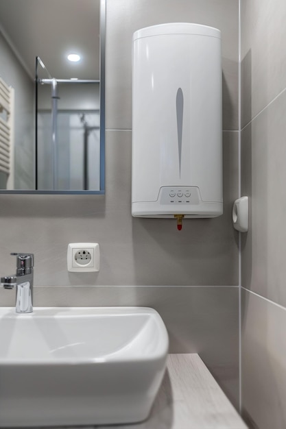 Closeup water heater in a modern bathroom with mirror and washbasin sink