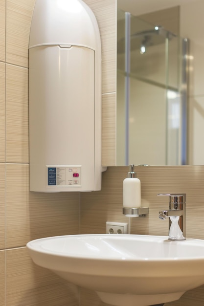 Closeup water heater in a modern bathroom with mirror and washbasin sink