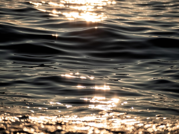 Closeup of water rippled surface with sunshine at sunset evening time