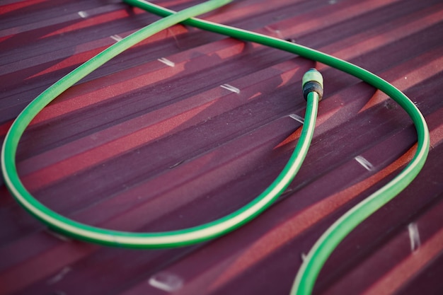 Closeup of a watering hose on a red roof in a garden