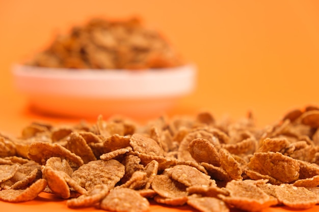 Closeup of wheat flakes on orange background quick cereal healthy breakfasts