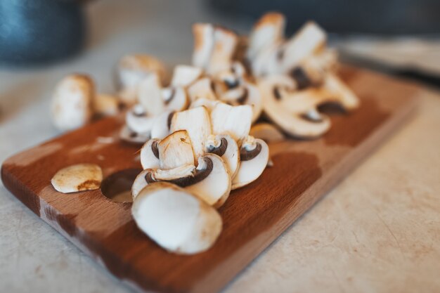 Closeup of white chopped champignon mushrooms, on the wooden plate.