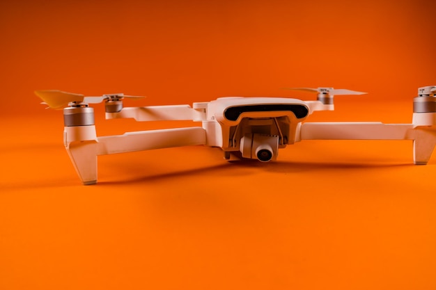 Closeup of white drone on orange background Modern drone unmanned aerial vehicle with propellers