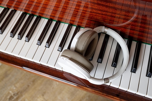 Closeup white headphones lie on the piano keys View from above