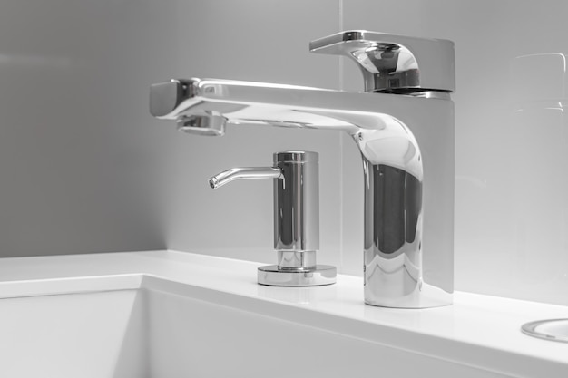 Closeup of white sink with large and small taps for filtering drinking running water concept of