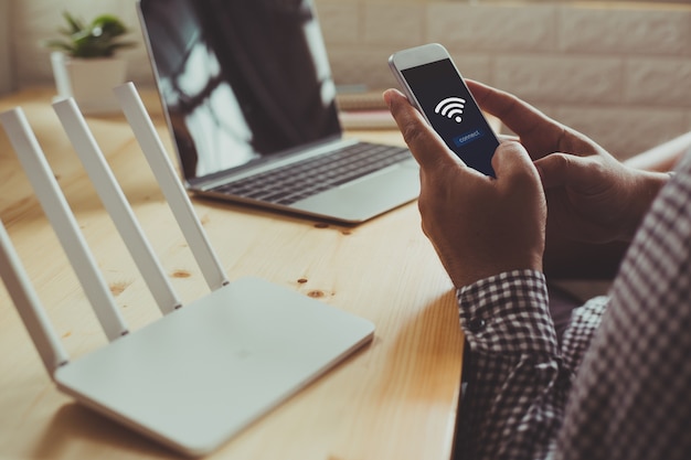 closeup of a wifi router and a man using smartphone 