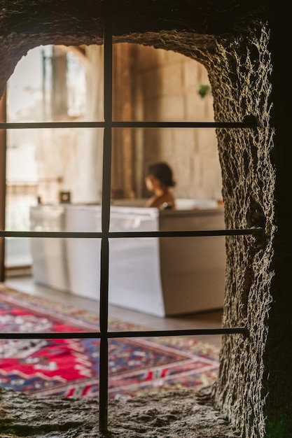 Closeup window with an outoffocus young woman relaxing in the bathtub of a hotel in Cappadocia Turkey