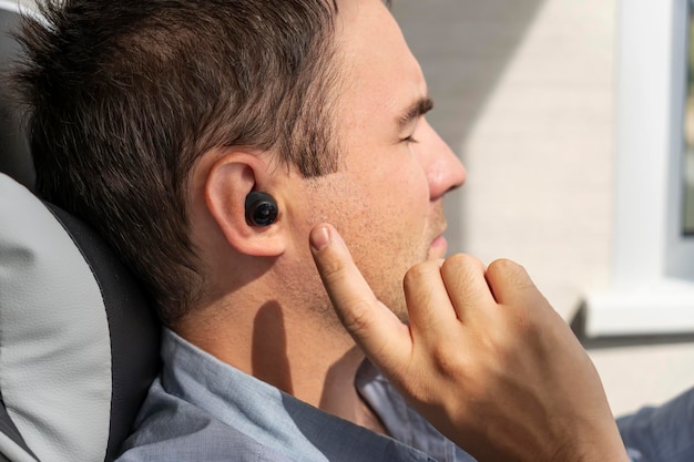 Closeup of wireless earphone in human ear insert earphone into the ear listening to music with headphones