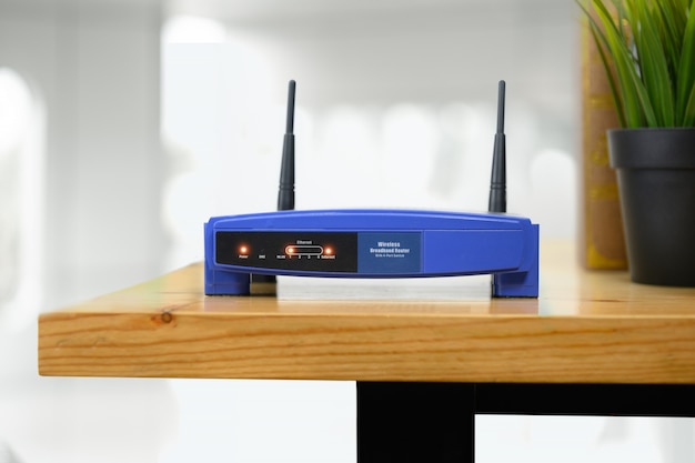 Closeup of a wireless router and a man using smartphone on living room at home office