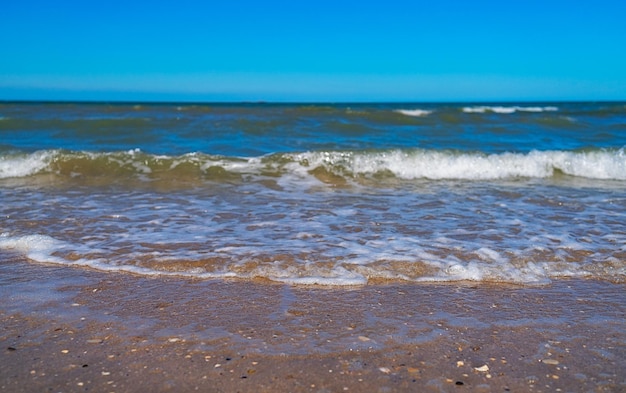 Closeup with waves of sea and sand on beautiful sunny day on beach