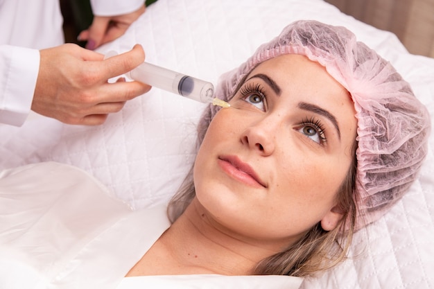 Closeup of woman applying ozone to her face for cosmetic treatment.