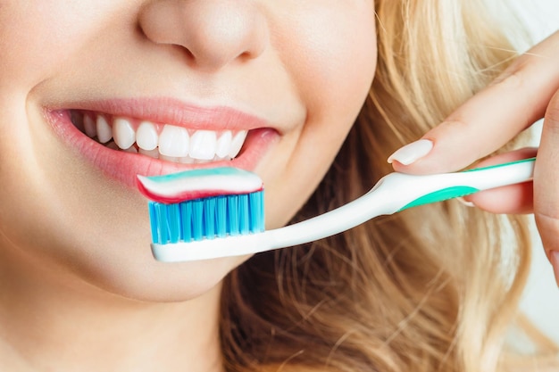 Closeup of woman brushing teeth the girl holds a toothbrush and smiles