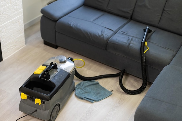 Closeup Of Woman Cleaning Sofa With Vacuum Cleaner At Home.