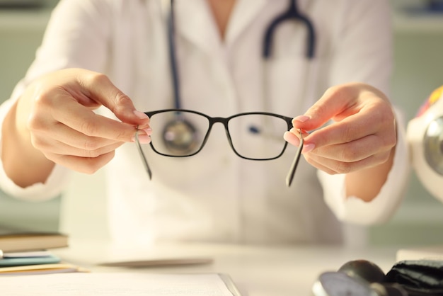 Closeup of woman doctor giving pair of black glasses to patient eyesight test and correction