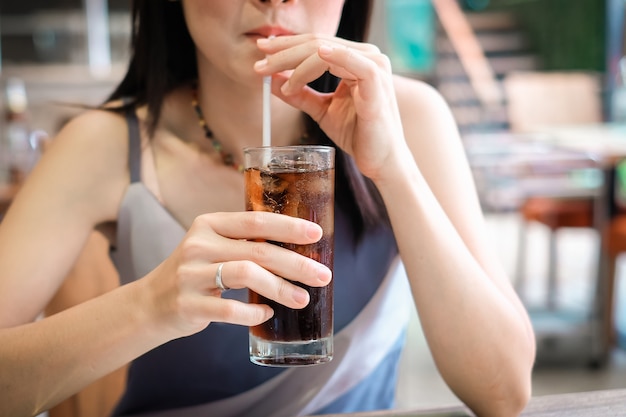 closeup woman drinking ice cola soda in the glass.food and beverage concept. 