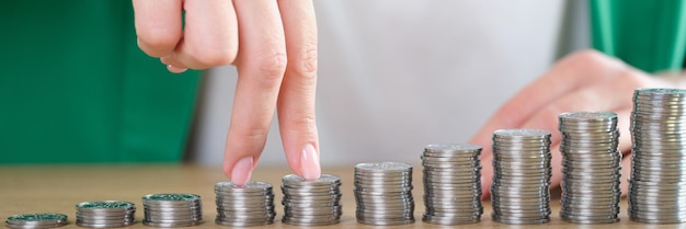 Closeup of woman fingers going up on bar chart collected of silver coins business growth