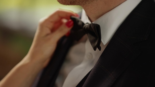 Closeup woman hands getting better bow tie outdoors Unknown newlywed couple standing before ceremony in park Unrecognizable bride touching groom before wedding in garden