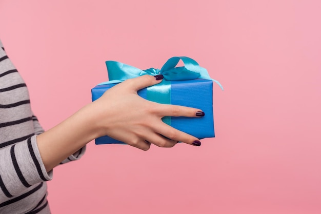 Closeup woman hands holding blue gift box romantic surprise for Valentine39s day elegant Christmas holiday present congratulation on birthday anniversary studio shot isolated on pink background