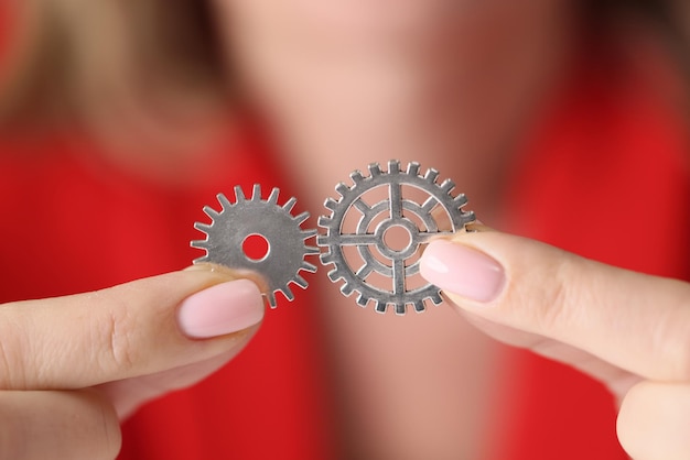 Closeup of woman hands holding and connecting metal gears teamwork teambuilding and single