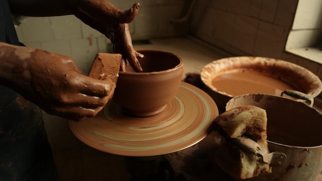 Closeup woman hands making clay pot in workshop Unrecognized artist sculpting from wet clay in studio Unknown female ceramist doing handmade product in pottery in slow motion