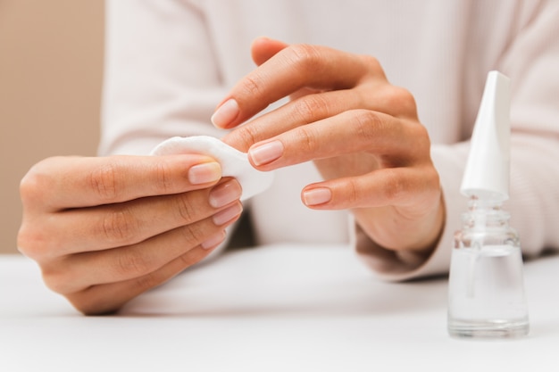 Closeup woman hands removing paint from nails with cotton pad