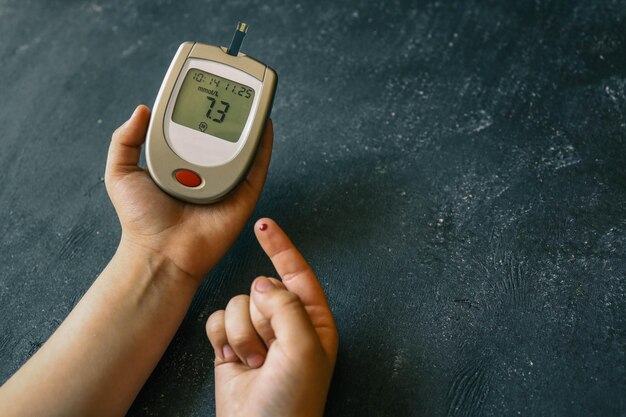 Photo closeup of woman hands testing high blood sugar with glucometer