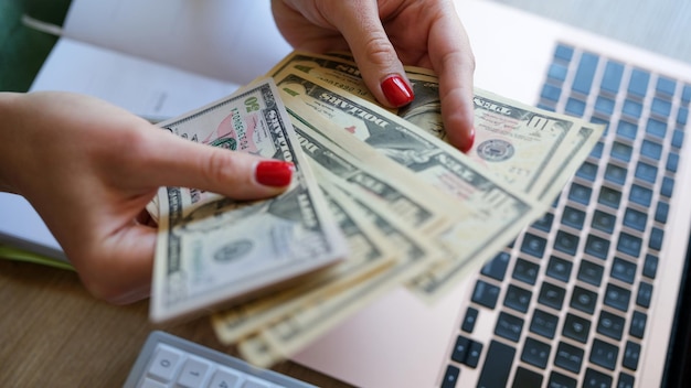 Closeup of woman holding cash in hand and counting banknotes financial accounting plan earned