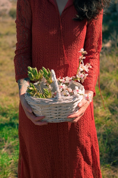 Closeup of a woman holding a white basket with almond tree flowers