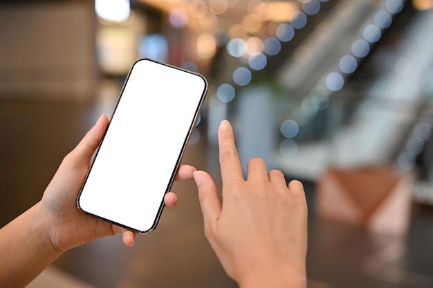 Closeup A woman holding a white screen mobile phone over blurred shopping mall background