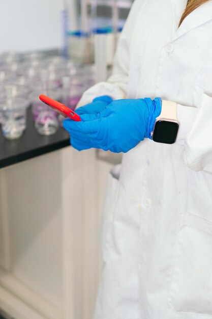 Closeup of Woman in Lab Coat Using Phone in Lab