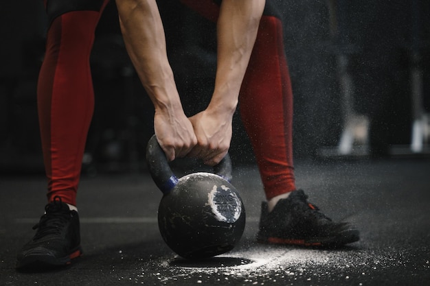 Closeup of woman lifting heavy kettlebell at gym