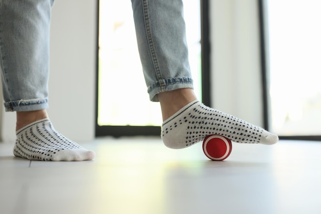 Closeup of woman massaging foot with ball to eliminate feet tension female person in jeans and