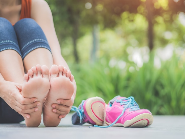 Photo closeup woman massaging her painful foot while exercising