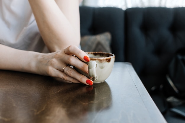 Closeup of woman's hand holding cup of hot beverage