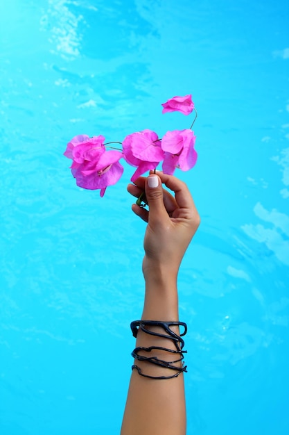 Closeup of woman's hand holding flower in her hand by the pool holiday and fashion concept