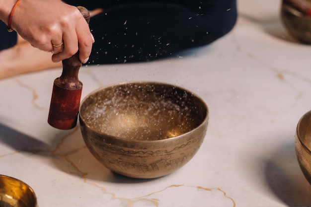 Closeup of a woman's hand playing on a Tibetan bowl filled with water