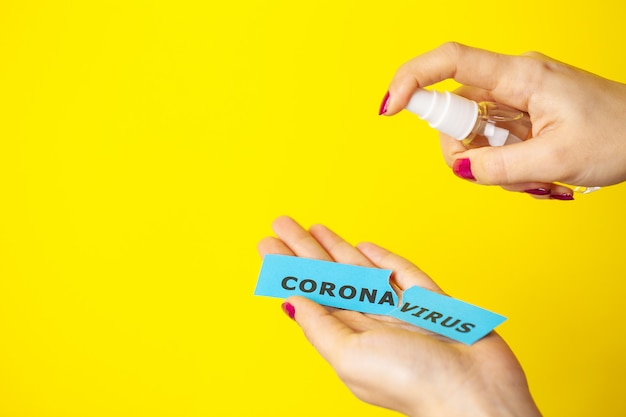 Closeup of woman spraying antiseptic on coronavirus inscription