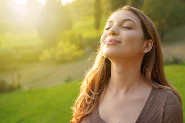 Closeup woman at sunset relaxing breathing fresh air