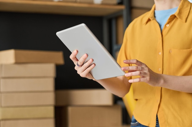 Closeup of woman using digital tablet to check track number while working in warehouse