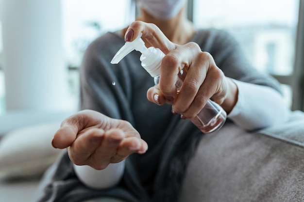 Closeup of woman using hand sanitizer while disinfects her hands at home