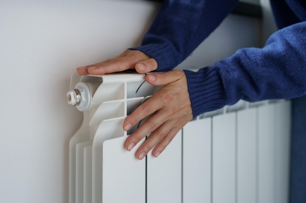 Closeup of woman warming her hands on the heater at home during cold winter days Heating season