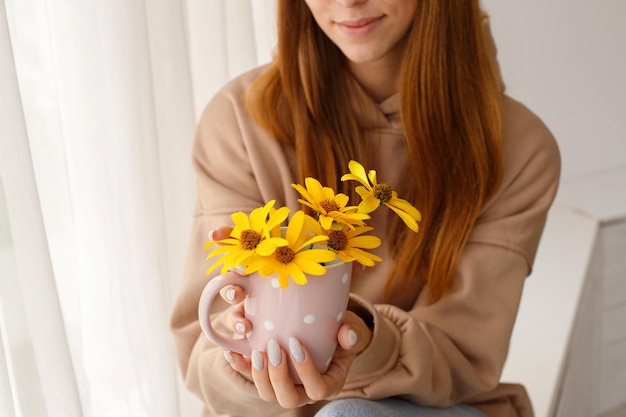 Closeup woman with a cup of flowers conceptual