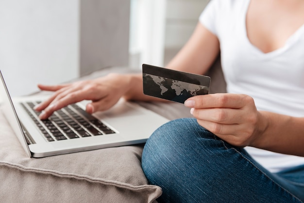 Closeup of woman with laptop and credit card doing online shopping at home