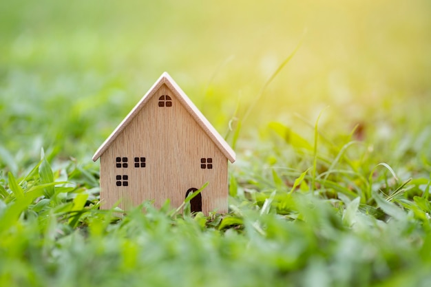 Closeup wood model house on sunlight grass background