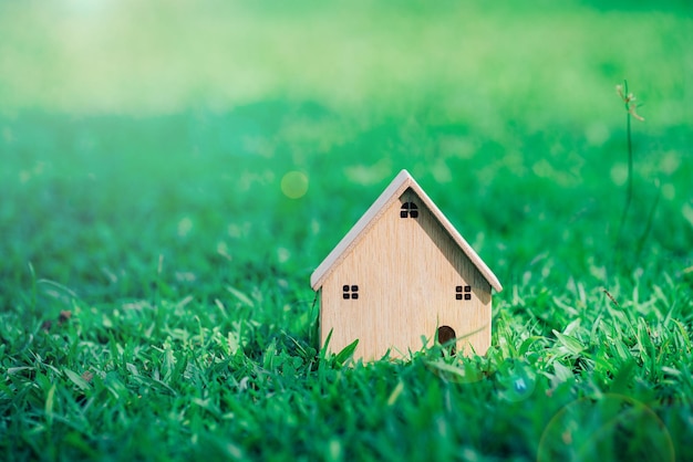 Closeup wood model house on sunlight grass background