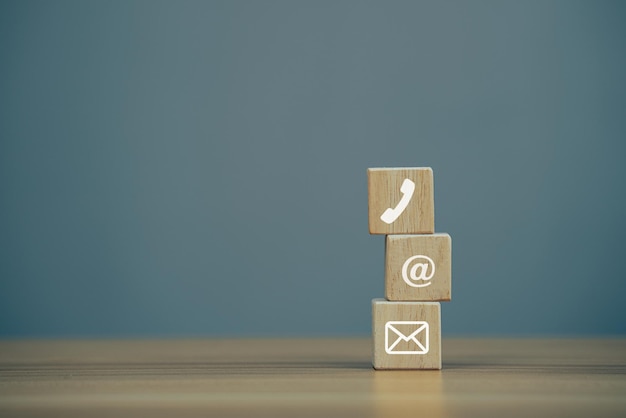 Closeup wooden block cube with symbol email address telephone on wooden table