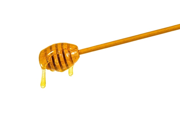 Closeup of a wooden dipper with pouring golden honey isolated on white background