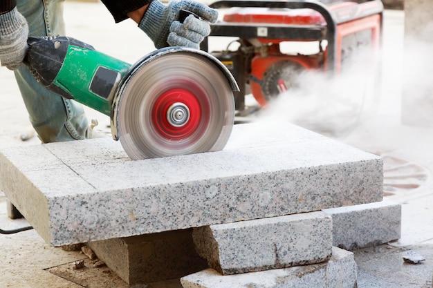 Closeup of worker cutting granite slab with grinder Dust while grinding stone pavement