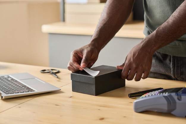 Closeup of worker packing order in the box at table and sticking note with track number on it